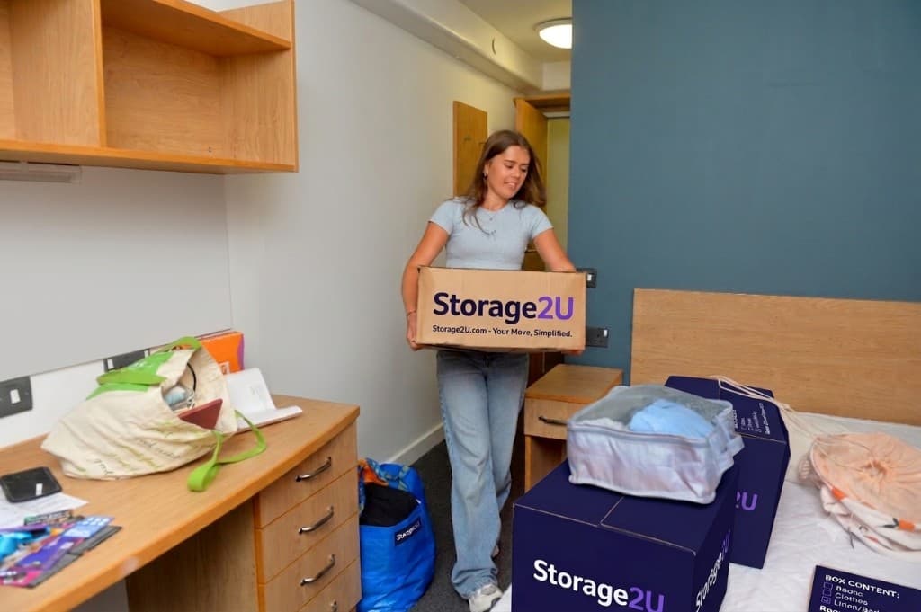 Student carrying a Storage2U box into a dorm room on move-in day
